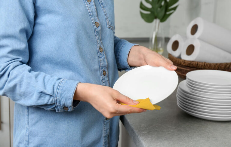 A woman wiping a plate with a small microfiber kitchen towel
