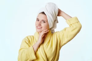 A woman in yellow dress with a microfiber towel wrapped around her head